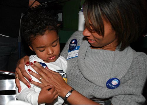 한 어머니가 미국 최초의 흑인 대통령 탄생을 축하하며 아이의 가슴에 '오바마-바이든' 스티커를 붙여주고 있다.
