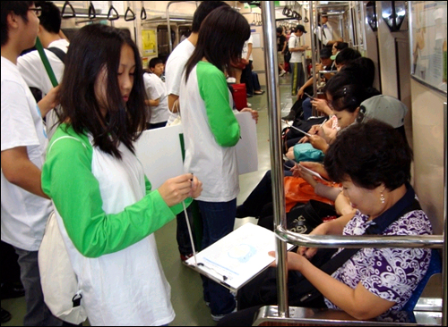 지하철에서 시민들에게 '환경지키기 10가지 약속 실천운동 서명을 받고 있는 학생들