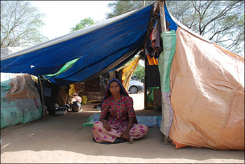 코히야네 가족이 지내는 천막 안에 앉아 있는 딸. 다른 가족들은 일을 찾아 나가고 없다.