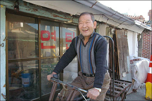 그의 애마(짐 자전거)를 타고 환하게 웃는 곽종만 할아버지. 지금 타고 있는 짐자전거는 나오지도 않는다고 한다. 