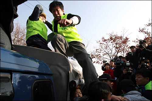 탈북자인 자유북한운동연합 박상학 대표가 화물차 지붕에 올라가서 진보단체 회원을 발로 차고 있다.