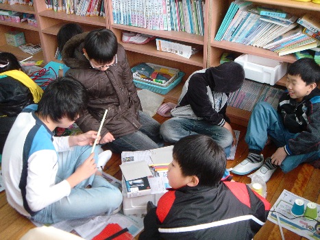 교실 바닥에 앉아서 만들기에 열중하고 있는 아이들