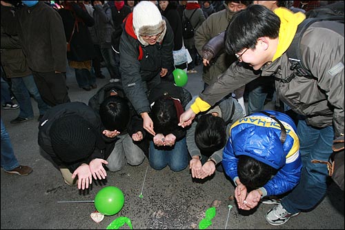 6일 저녁 서울 명동에서 민주민생국민회의 주최로 열린 '경제파탄 민주파괴 이명박 정권 심판 국민대회'에서 대학생들이 구걸하는 퍼포먼스를 벌이자 다른 참가자들이 동전을 던져주고 있다.