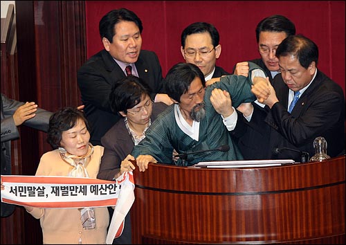 2008년 12월 12일 밤 서울 여의도 국회 본회의장에서 강기갑 대표와 민주노동당 의원들이 감세법안에 반대하며 시위를 벌이다가 한나라당 의원들에게 끌려 내려가고 있다. 