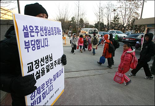  '일제고사'때 학생들의 야외체험학습을 허락한 뒤 서울시교육청으로부터 해임통보를 받은 설은주 교사가 근무하는 서울 강북구 수유동 유현초등학교 앞에서 지난해 12월 15일 한 학부모가 피켓시위를 벌이고 있다.