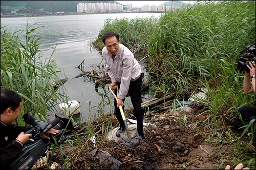 대선 후보이던 2007년 6월 22일, 이명박 대통령이 한반도 대운하를 대선 공약으로 내건 뒤 부산시 강서구 대저동 낙동강 하구에서 뻘을 삽으로 뜨고 있다.