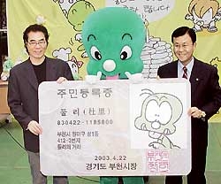 2003년 만화의 도시 부천에서 김수정 화백이 둘리의 주민등록증과 함께 포즈를 취하고 있다