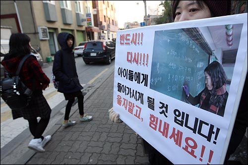 18일 오전 서울 광진구 광양중학교에서 윤여강 교사가 출근투쟁을 벌인 가운데 인근학교 교사가 나와 부당한 징계 철회를 요구하며 손피켓을 들어보이고 있다.
