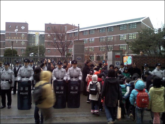 거원초등학교 교문을 막고 서있는 경찰들. 아이들이 좁은 문으로 등교하고 있다.