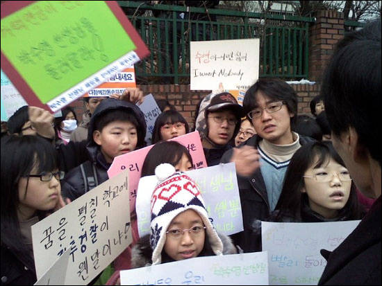 출근을 가로막고 있는 거원초등학교 교장 선생님에게 항의하고 있는 박수영 선생님과 아이들