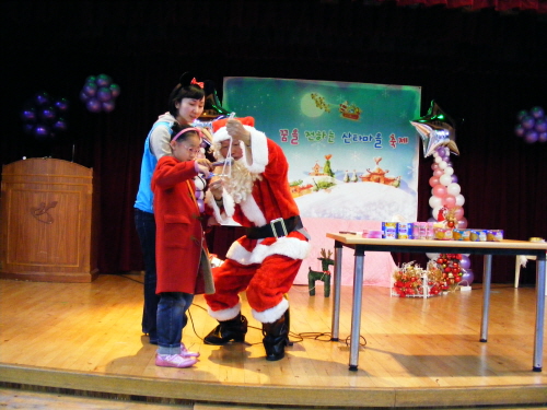 산타로 분한 어르신이 축제에 참여한 한 아이에게 마술시범을 보여주고 있다.