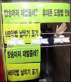 민주당 의원들이 본회의장을 기습 점거한 가운데 26일 오전 서울 여의도 국회에서 민주당 의원들이 점거한 본회의장 입구 유리창에 'MB악법' 관련 문구를 붙이고 있다.