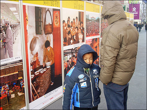 왕푸징 거리에서 '개혁개방 30주년 사진대전'을 관람하고 있는 부자. 