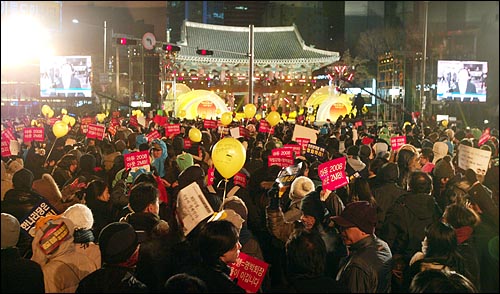 31일 밤 새해 보신각 타종식이 열리는 서울 종각 네거리에 모인 시민들이 '이명박 퇴진' '아듀 2008 아듀 MB!' '언론관계법 개악 철회하라' 등의 구호가 적힌 종이피켓과 '선생님을 돌려주세요'가 적힌 노란풍선을 들고 있다.
