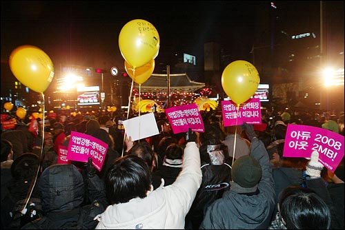 31일 밤 새해 보신각 타종식이 열리는 서울 종각 네거리에 모인 시민들이 '이명박 퇴진' '아듀 2008 아듀 MB!' '언론관계법 개악 철회하라' 등의 구호가 적힌 종이피켓과 '선생님을 돌려주세요'가 적힌 노란풍선을 들고 있다.