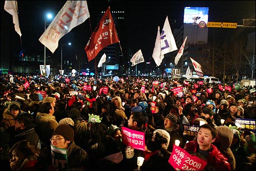 1일 새벽 서울 종로 보신각에서 2009년 새해를 알리는 타종식이 열리는 가운데, 이명박 정권을 규탄하는 피켓과 촛불을 든 시민들이 '이명박 퇴진'을 외치고 있다.