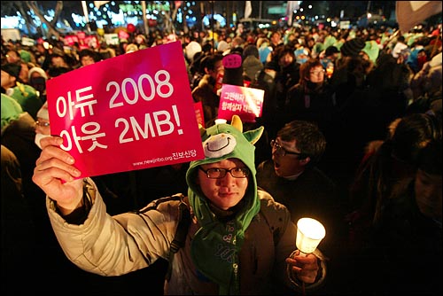 1일 새벽 서울 종로 보신각에서 2009년 새해를 알리는 타종식이 열리는 가운데, 촛불을 든 한 시민이 '아듀 2008, 아웃 2MB!'가 적힌 종이피켓을 들고 있다.