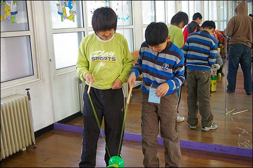 아이들이 대만의 전래놀이인 실팽이돌리기를 열심히 배우고 있다 
