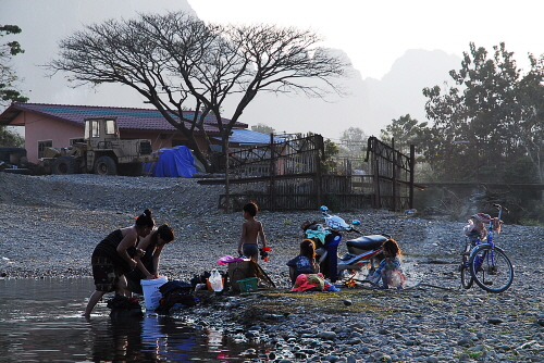 현지인들이 강가에서 빨래와 목욕을 하고 있다