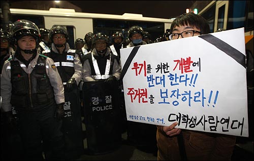 21일 저녁 서울 용산구 신용산역 부근 참사 현장에서 열린 '용산철거민 살인진압 이명박 규탄 및 희생자 추모대회' 에서 한 대학생이 철거민들의 주거권 보장을 요구하며 손피켓을 들어보이고 있다.