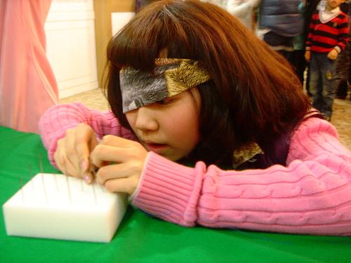 장애 체험 캠프에 참가한 윤은채 어린이가 한쪽 눈을 가린 채 열심히 바늘에 실을 꿰고 있다.