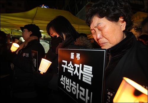  전국철거민연합회 회원들과 시민들이 28일 저녁 서울 용산구 신용산역 부근 참사 현장에서 열린 추모집회에서 경찰의 강제진압에 사망한 고인들을 추모하며 눈물을 흘리고 있다.