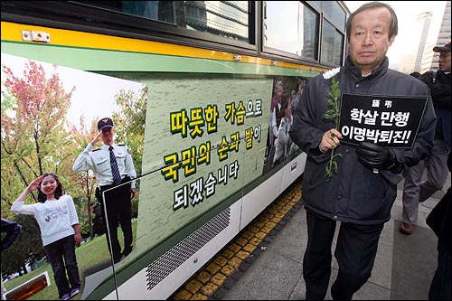 31일 오후 서울 청계광장에서 열릴 예정인 '용산 철거민 살인진압 희생자 제2차 범국민추모대회'를 경찰이 원천봉쇄한 가운데, 광장에 미리 들어온 일부 참석자들이 대국민홍보 문구가 붙은 경찰버스옆을 지나고 있다.