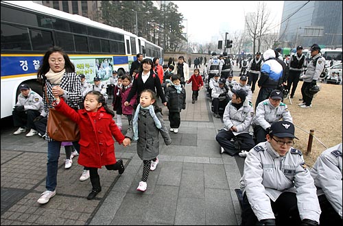 7일 오후 '용산철거민참사 희생자 제3차 추모범국민대회'가 열릴 예정인 서울 청계광장 주변을 경찰병력이 겹겹이 에워싸서 원천봉쇄하고 있는 가운데 어린이들이 경찰들 곁을 지나고 있다.