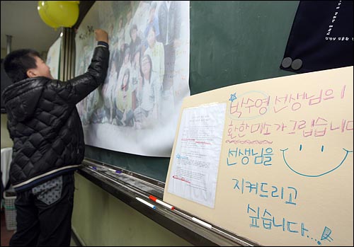 학생들이 대형 현수막으로 만든 기념사진에 바램의 글귀를 적고 있다.