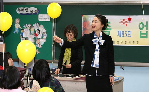  김윤주 교사가 '우리 선생님을 돌려주세요'가 적힌 노란풍선을 보며 웃고 있다.