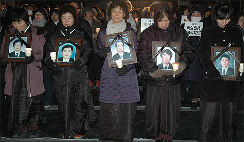 2월 20일, 용산참사 한 달을 맞아 참사 현장에서 열린 촛불집회에 참석한 유족들이 영정을 들고 서있다.
