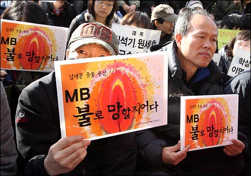 3월 28일 오후 서울 중구 프레스센터앞에서 열린 '용산철거민참사 책임자 처벌 및 MB악법 저지 범국민대회' 참가자들이 '남대문, 촛불, 용산 - MB 불로 망할지어다'가 적힌 손피켓을 들고 있다.
