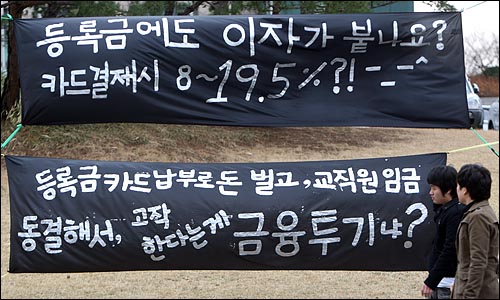 연세대학교 학생들이 3일 오후 서울 서대문구 연세대학교 교정에 내걸린 '높은 이자의 등록금 카드납부를 반대한다'는 내용의 현수막 앞을 지나고 있다.