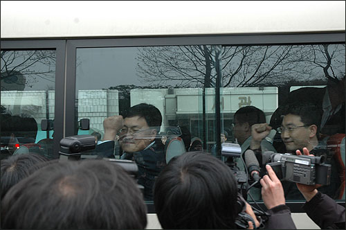 영장실질심사를 마친 뒤 호송버스에 오른 현덕수 기자(오른쪽)와 조승호 기자가 동료들에게 주먹을 쥐어보이고 있다. 