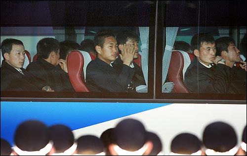 북한선수단 대부분이 굳은 표정으로 웃음을 보이지 않는 가운데 정대세 선수(가운데)가 취재진을 향해 손을 들어보이고 있다.