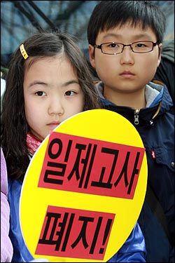 일제고사폐지전국시민모임 회원들이 지난 3월 31일 오전 서울 세종로 동화면세점앞에서 일제고사를 거부하고 아이들과 함께 체험학습을 떠나기에 앞서 기자회견을 열고 있는 가운데, 체험학습에 참여한 학생들이 '일제고사 폐지' 손피켓을 들고 있다.