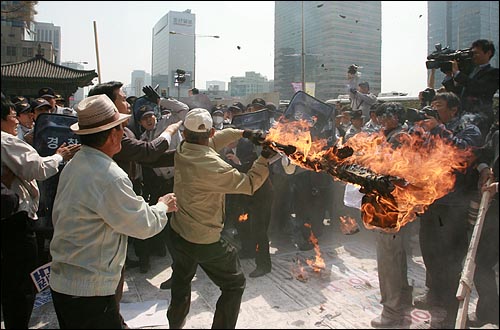  지난해 4월 6일 오후 어버이연합 등 보수단체 회원들이 서울 광화문 교보빌딩앞에서 '북한 미사일 발사 도발 규탄 및 UN안보리 대북제재 강력대처 촉구 긴급 기자회견'을 열던 도중, 북 미사일 모형 화형식을 제지하는 경찰을 향해 한 회원이 불붙은 각목 피켓을 휘두르고 있다.