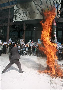 박찬성 반핵반김국민협의회 대표가 불 붙은 북한 미사일 모형에 기름을 붇고 있다.