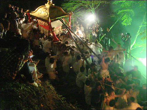 마을사람들이 신 가마를 어깨에 메고 산에서 내려오고 있다.