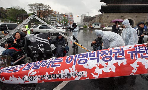  제29회 장애인의 날인 20일 오후 서울 종로구 동대문 앞 사거리에서 장애인들이 휠체어에 쇠사슬과 사다리를 묶고 장애인 차별철폐와 장애인생존권 9대 요구안을 요구하며 도로 점거 기습시위를 벌이고 있다.