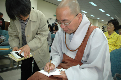 법륜 스님은 21일 창원에서 강연하기에 앞서 한 참석자한테 책에 서명하고 있다.