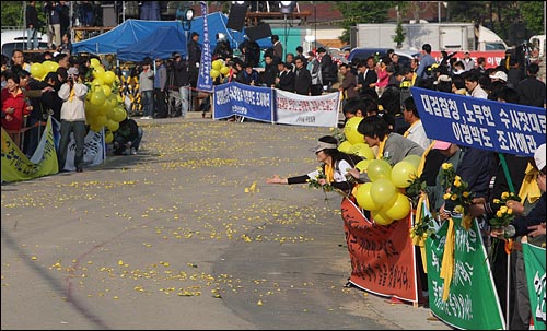 30일 오전 경남 김해시 봉하마을 노무현 전 대통령 사저 앞 도로에서 노사모(노무현을사랑하는사람들의모임) 회원들과 지지자들이 노란 장미를 길가에 던지며 배웅준비를 하고 있다.