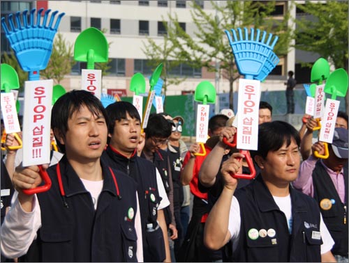 거리행진을 벌이고 있는 노동자들이 '삽집 정책 중단'을 촉구하면서 삽 모형을 들고 퍼포먼스를 벌이고 있다.
