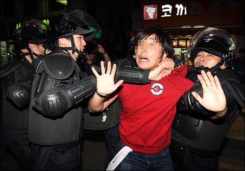 경찰들이 한 시위자의 목을 조르며 강제연행하고 있다.
