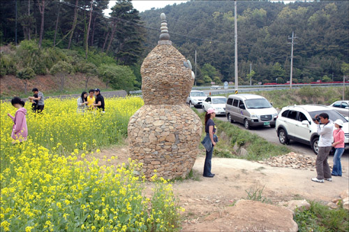 거제시 캐릭터인 몽돌이 몽순이를 형상화한 돌탑을 배경으로 관광객이 사진을 찍고 있다.
