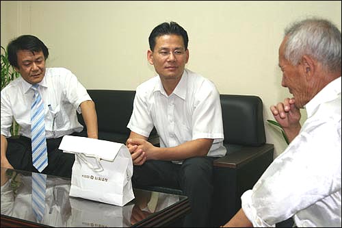 김해성 목사(왼쪽 끝)가 입회한 가운데 김종주(가운데) 변호사가 보상금을 전달하려고 하자 전영남 할아버지가 눈물을 흘리고 있다. 