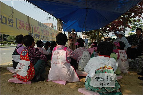  앞치마에 천에 대고 구호를 적었다. 어버이날, 할머니들은 카네이션 대신 구호 적힌 앞치마를 두르고 1인 시위를 하고 있다.