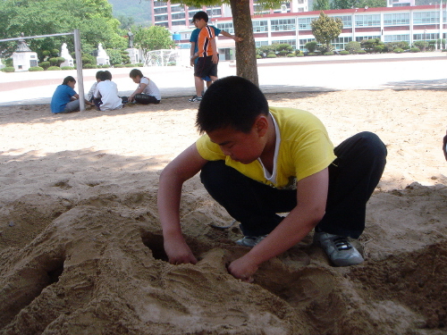 모래성쌓기 놀이 하나로 터널을 만들고 있는 아이