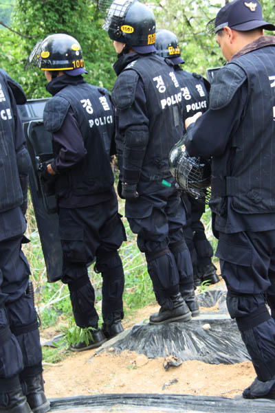 고추모종을 심기 위해 밭이랑에 씌워놓은 검은비닐을 경찰들이 밟고 서 있다.