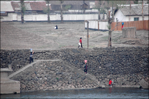 북한 양강도 중부 압록강 연안에 있는 혜산시. 북한 주민들이 강변에 나와 빨래하고, 양동이로 물을 길러가는 모습이 보인다.